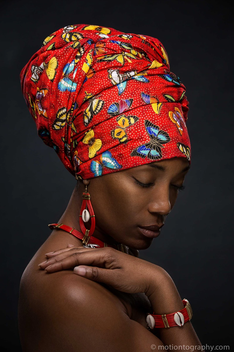 Studio portrait with red African headwrap and jewelry by Motiontography