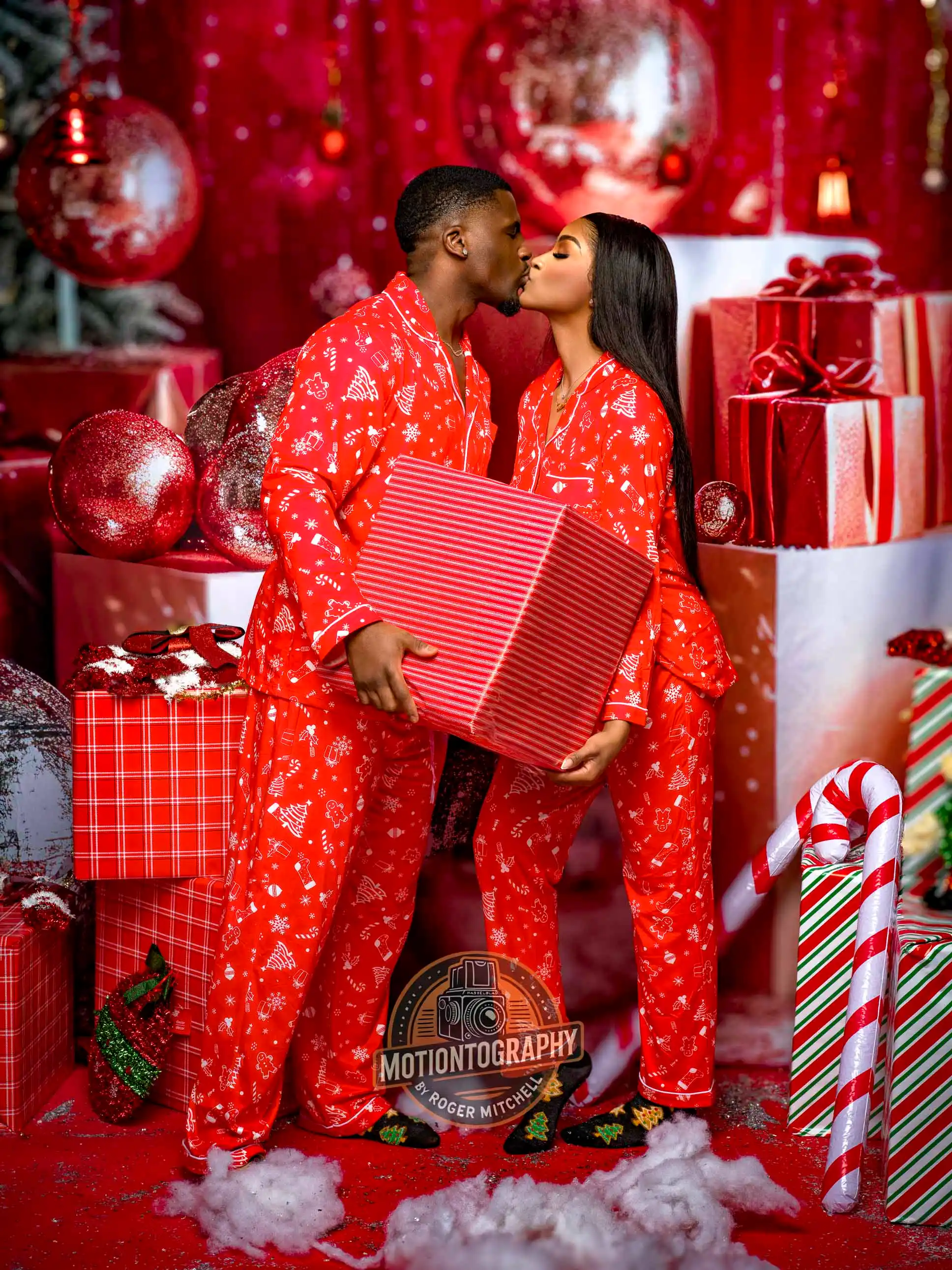 couple kissing matching red christmas pajamas giant gift by Motiontography