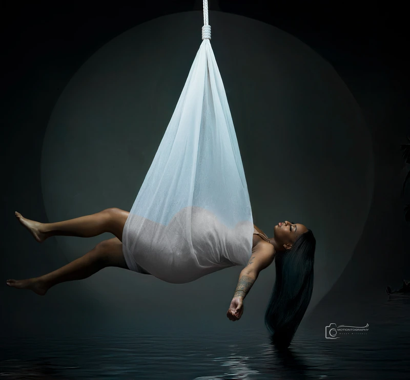 pregnant woman floating in white hammock maternity portrait by Motiontography