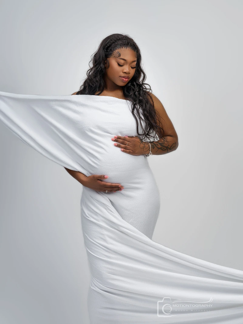pregnant woman in white flowing dress maternity photo by Motiontography